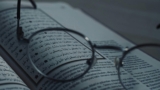 Close-up of eyeglasses on a book with Arabic script, symbolizing knowledge and learning.