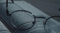 Close-up of eyeglasses on a book with Arabic script, symbolizing knowledge and learning.