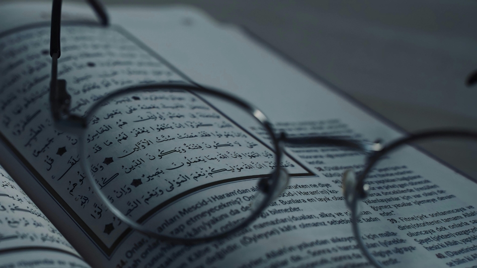 Close-up of eyeglasses on a book with Arabic script, symbolizing knowledge and learning.