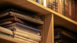 A stack of Islamic religious books on a wooden shelf, highlighting Arabic scripts and cultural significance.