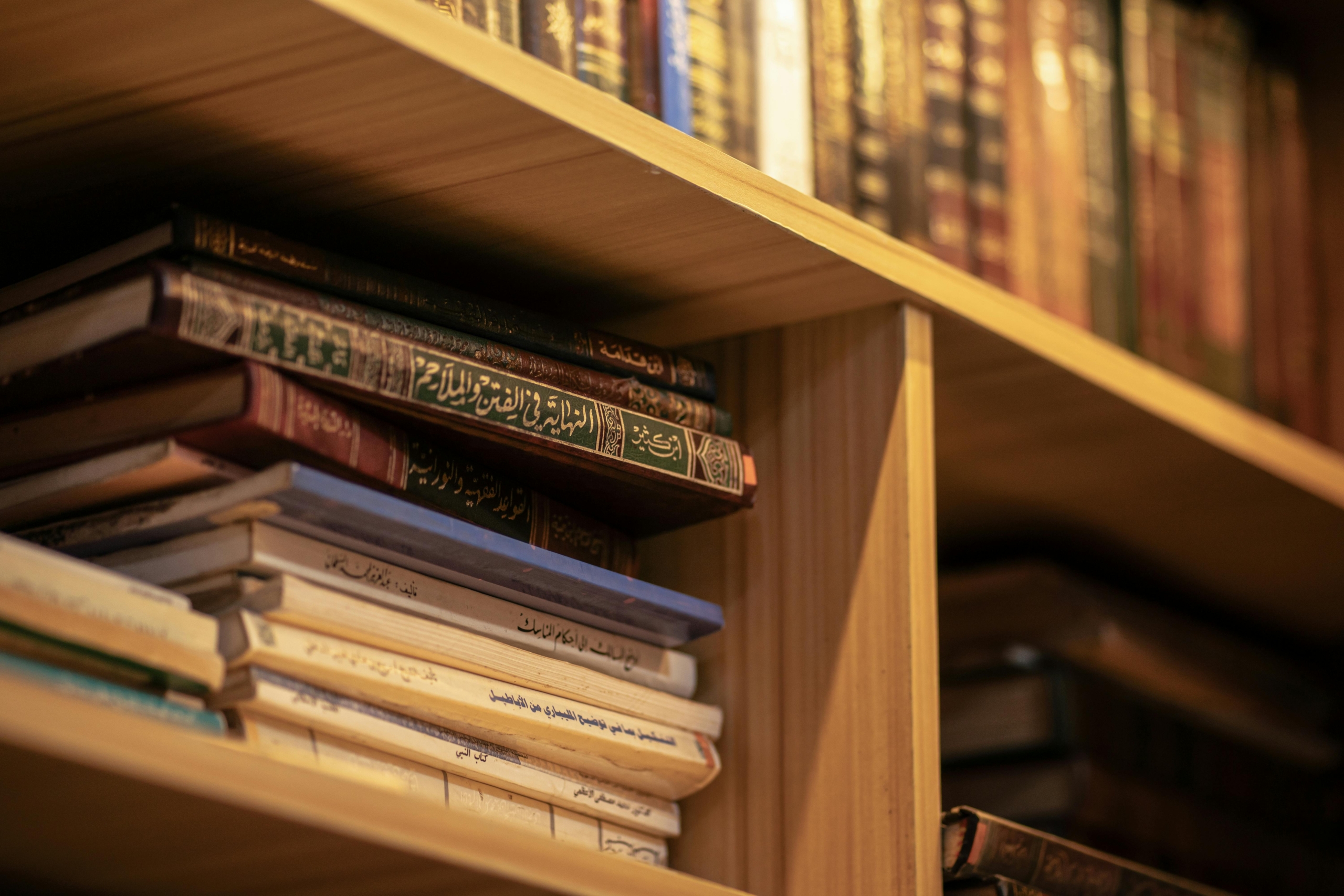 A stack of Islamic religious books on a wooden shelf, highlighting Arabic scripts and cultural significance.