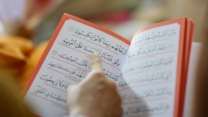 Close-up of a person reading an Arabic text, highlighting cultural education and learning.