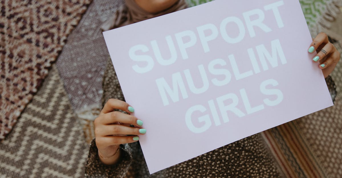 Woman holding a sign with 'Support Muslim Girls' on patterned background.