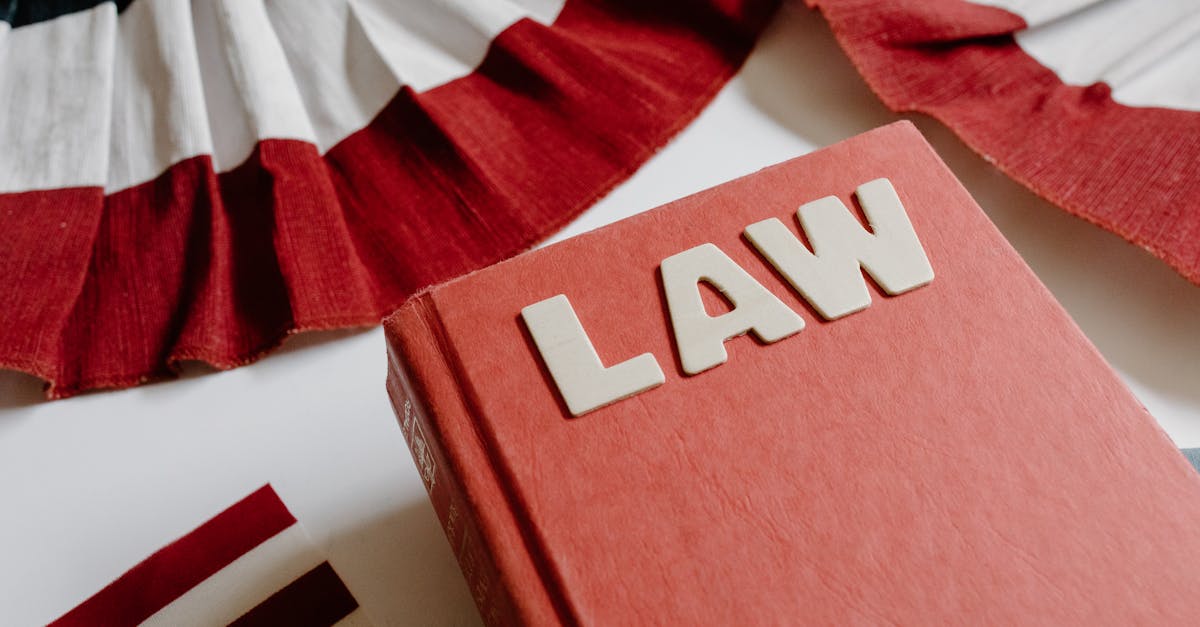 A law book with bold letters placed beside a red, white, and black decorative ribbon.